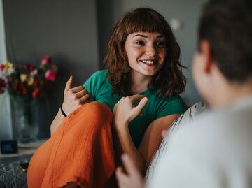 Frau mit freundlichem Lächen unterhält sich mit einem Mann auf der Couch | © AdobeStock/ qunica.com