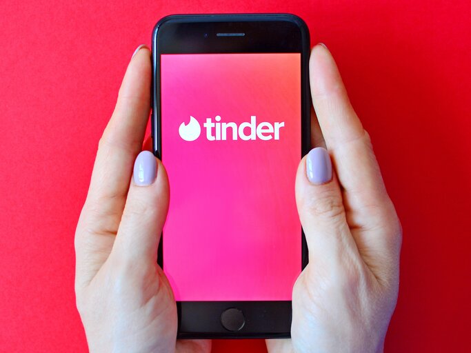 Frau hält Smartphone in der Hand. Tinder App Logo wird angezeigt | © shutterstock/Varavin88