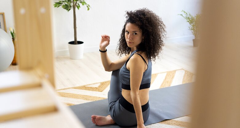 Frau macht Rückenübungen auf einer Yogamatte zu Hause | © GettyImages/	Westend61